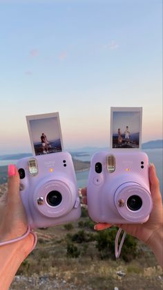 two people holding up polaroid cameras to take pictures