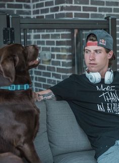 a man sitting on a couch next to a dog with headphones in his ears