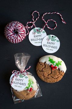 three cookies and two candy canes on a black surface with happy holidays stickers