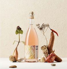 a bottle of wine sitting on top of a table next to some vegetables and nuts