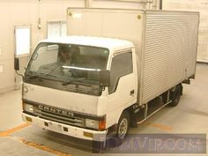 a man sitting in the driver's seat of a white truck parked in a garage