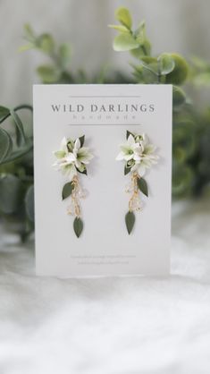 two white flowers and green leaves are on top of a card that says wild darings