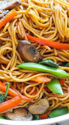 a pan filled with noodles and vegetables on top of a marble counter