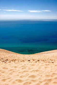 an ocean view from the top of a sand dune with blue water in the background