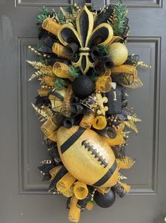 a yellow and black football wreath hanging on a gray door with gold decorations around it