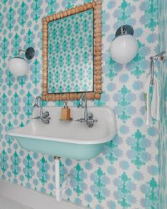 a white sink sitting under a mirror in a bathroom next to a wall mounted faucet