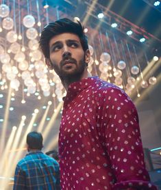 a man standing in front of a chandelier with lots of lights hanging from it