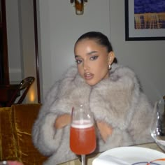 a woman sitting at a table with a drink in front of her