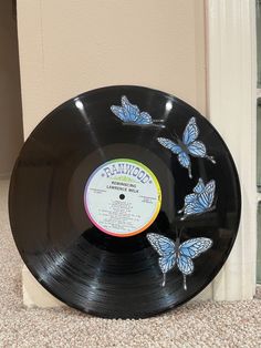 a record with butterflies painted on it sitting in front of a window sill next to a door