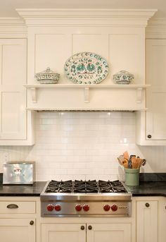 a stove top oven sitting inside of a kitchen next to white cabinets and counter tops