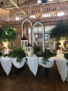 the table is set up with white linens and greenery