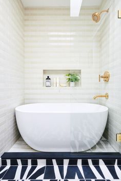 a white bath tub sitting inside of a bathroom next to a tiled floor and wall