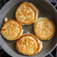 four pancakes cooking in a frying pan on the stove