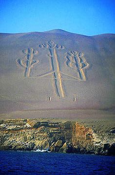 an image of the cross carved into the sand on top of a mountain by water