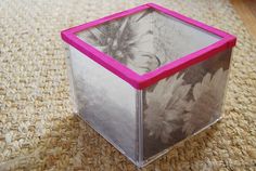 a pink and clear box sitting on top of a carpeted floor next to a rug