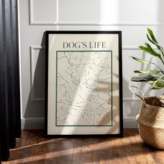 a dog's life poster sitting on top of a wooden floor next to a potted plant