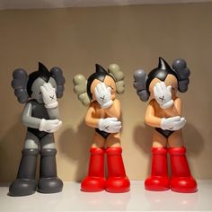 three figurines in the shape of cartoon characters are lined up on a shelf