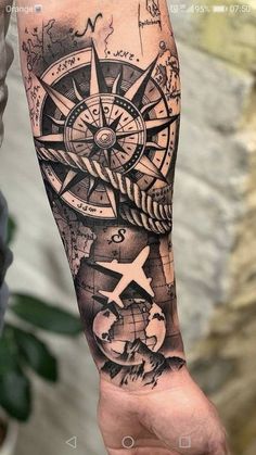 a man's arm with a compass and world map tattoo on the left forearm