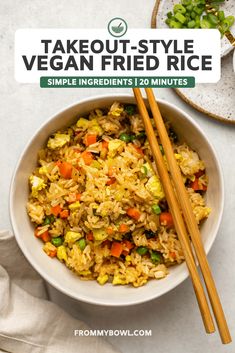 a bowl filled with rice and vegetables next to chopsticks on a white surface