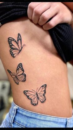 a woman's stomach with three butterflies on the side, and one is black