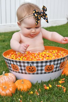 a baby sitting in a bowl filled with candy corn