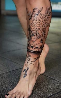 a woman's legs with tattoos and flowers on her leg, in front of a tiled floor