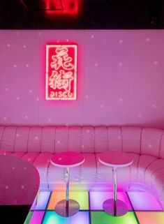 a brightly lit room with white leather couches and neon colored lights on the walls