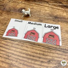 a small toy dog standing on top of a wooden table next to a red barn