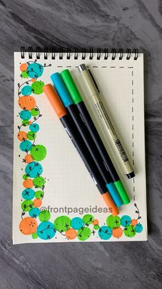 three pens sitting on top of a notebook