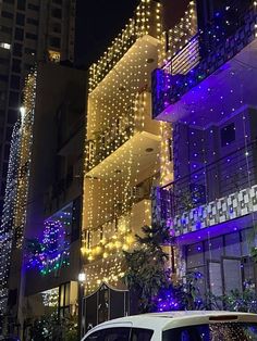 a white van parked in front of a tall building with christmas lights all over it