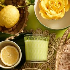 a table topped with plates and bowls filled with lemons next to a yellow rose