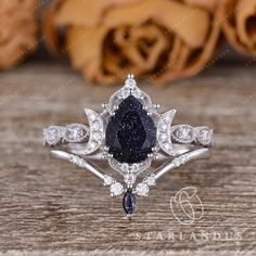 a diamond and blue sapphire engagement ring on a wooden table with rose petals in the background