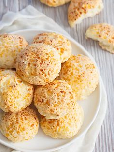 a white plate topped with cheesy biscuits on top of a table next to a napkin