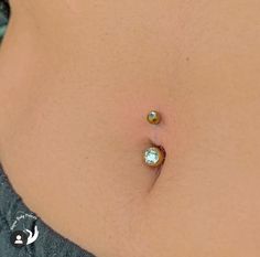 a woman's stomach with two piercings on it