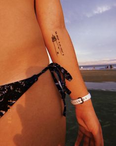 a woman with a small tattoo on her left arm and the ocean in the background