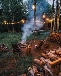 an outdoor fire pit surrounded by logs and string lights