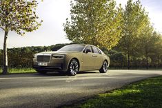 the car is parked on the side of the road in front of some trees and grass