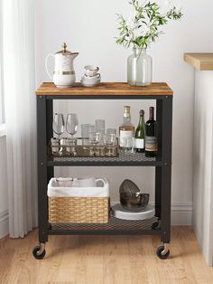 a bar cart with wine glasses and bottles on it