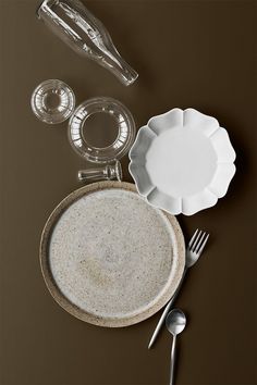 an empty plate and silverware on a brown table cloth next to utensils