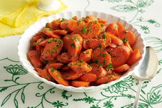 a white bowl filled with sliced carrots on top of a green and white table cloth