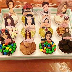 there are many cupcakes on the tray with different pictures and candies in them