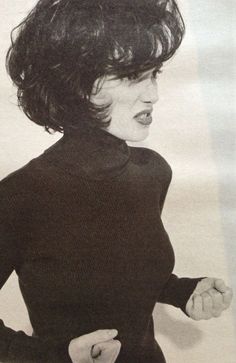 an old photo of a woman wearing a black sweater and holding her hands on her hips