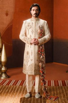 Beige sherwani with all over scattered floral gold tone sequin, cutdana embroidery, elevated with anarphool running through the sherwani in heavy  zardozi work. Paired with an inner kurta and pant. - Aza Fashions Luxury Embroidered Cotton Silk Sherwani, Luxury Raw Silk Bandhgala With Gold Embroidery, Luxury Off White Sherwani With Dabka Work, Luxury Pink Sherwani With Zari Work, Matka Kulfi, Raw Silk Embroidery, Embroidery Zardozi, Cutdana Embroidery, Zardozi Work