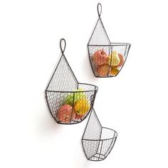 three metal baskets with fruit in them hanging on the wall