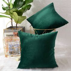 two green pillows sitting on top of a white bed next to a potted plant