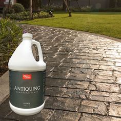 a gallon of antiquinne sitting on a brick walkway