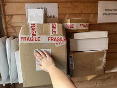 a person's hand reaching into a box with fragile stickers on it and other boxes in the background