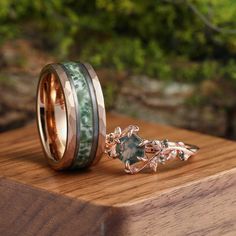 two wedding bands with green and pink wood inlays on top of each other