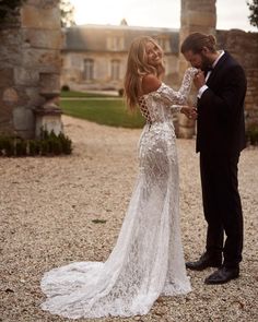 a man and woman standing next to each other in front of an old castle building