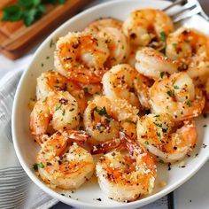 a white plate topped with cooked shrimp and garnished with parmesan sprinkles